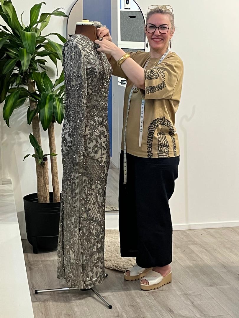 Staff adjusting an embellished dress on a mannequin